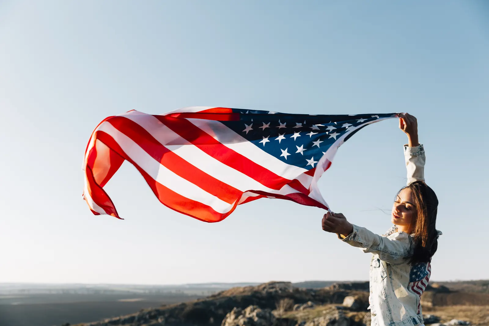 Mulher erguendo a bandeira dos Estados Unidos contra o céu: a conquista da última etapa